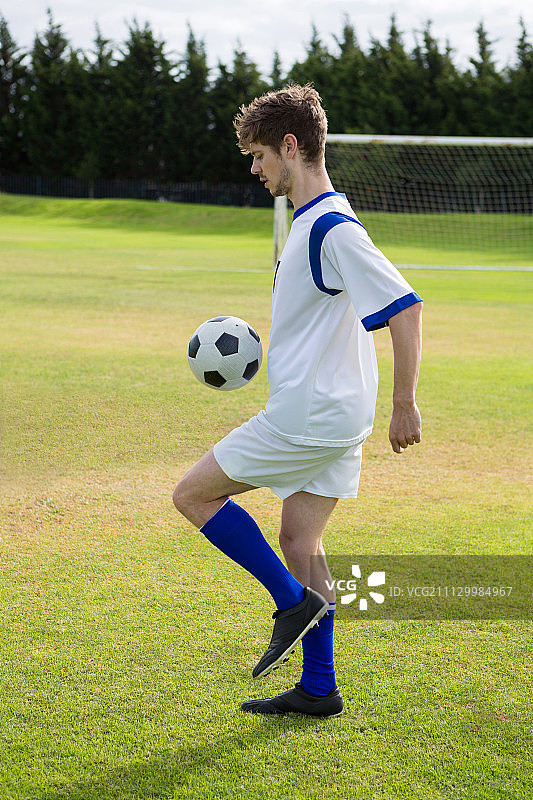 足球运动员在场上踢球的侧视图图片素材