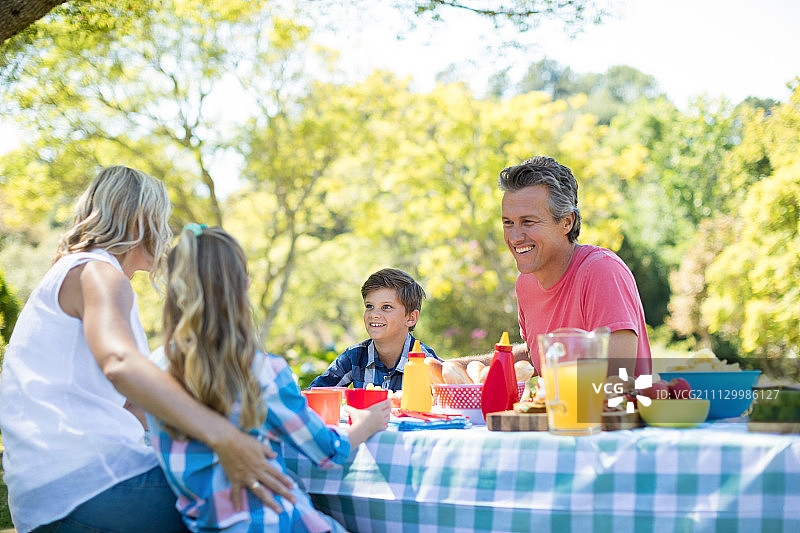 在一个阳光明媚的日子里，一家人在公园吃饭的时候互相交流图片素材