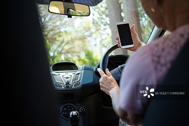 活跃的老年妇女在开车时使用手机图片素材