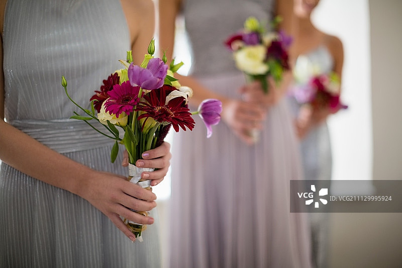 新娘站在中间，捧着花束在家图片素材