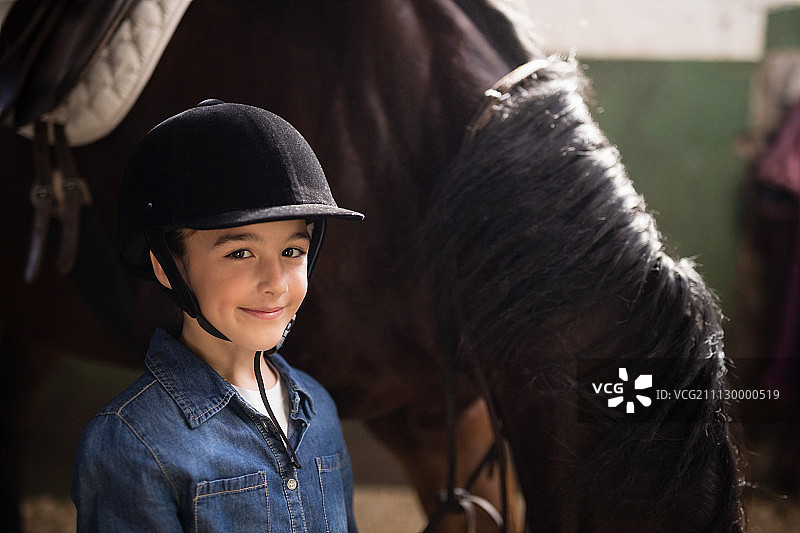 戴着头盔的女孩站在马旁边的肖像不稳图片素材
