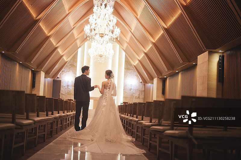 婚纱和燕尾服在婚礼大厅里牵手的照片图片素材