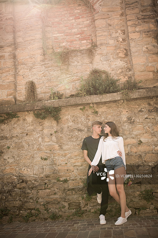一对年轻的夫妇靠着老砖墙图片素材