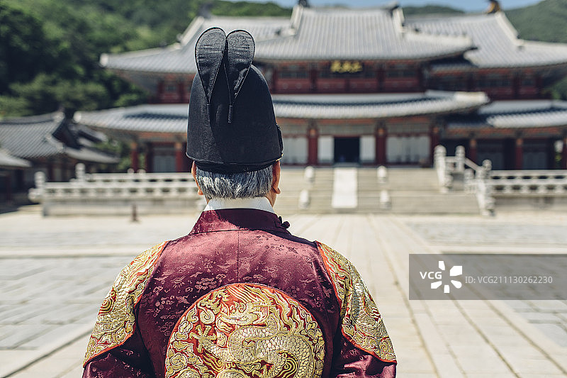 穿着韩国国王服装的高级男子站在皇宫里的后视图图片素材