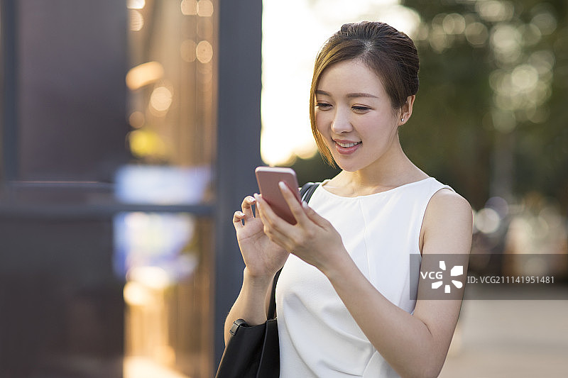 开心的年轻商务女子使用手机图片素材