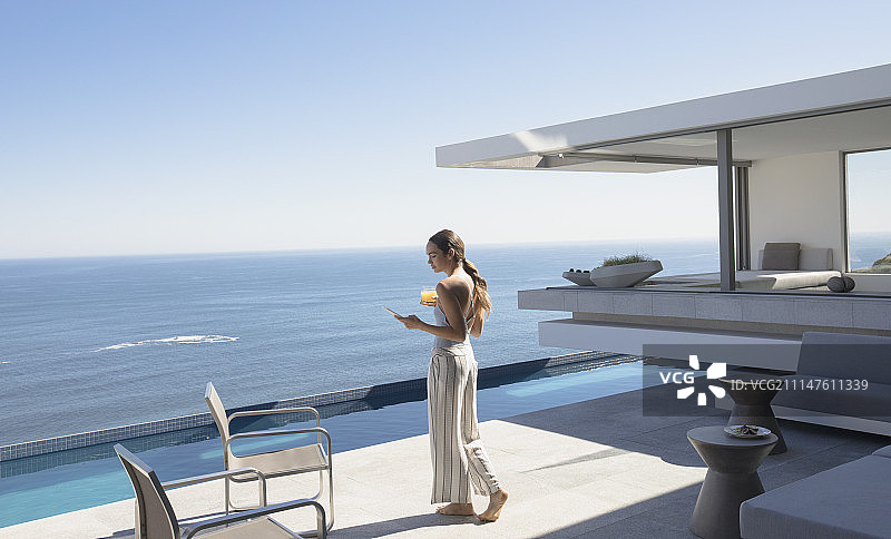 女人站在阳光明媚的豪华阳台上，可以看到海景图片素材