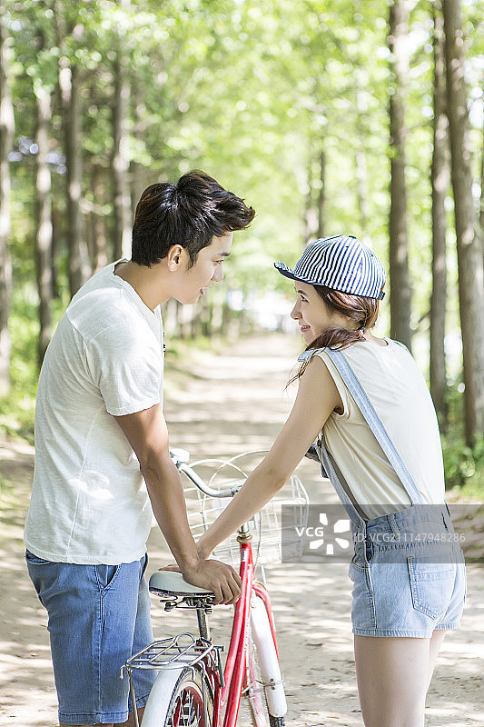 在公园里，一对情侣站在自行车旁边图片素材