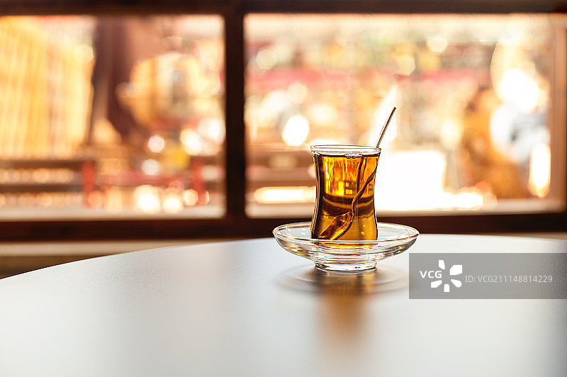 土耳其茶装在传统的玻璃杯里，放在室内靠近窗户的桌子上。反映了…图片素材