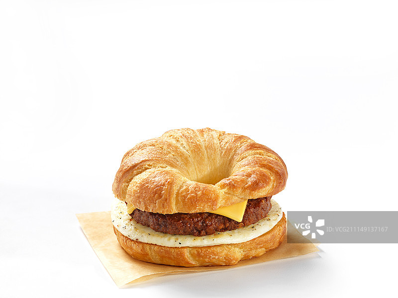 一个牛角面包汉堡配上奶酪和鸡蛋以衬托白色的背景图片素材