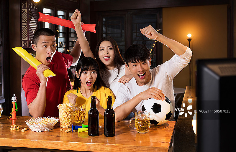 四个球迷在酒吧观看足球比赛庆祝胜利图片素材