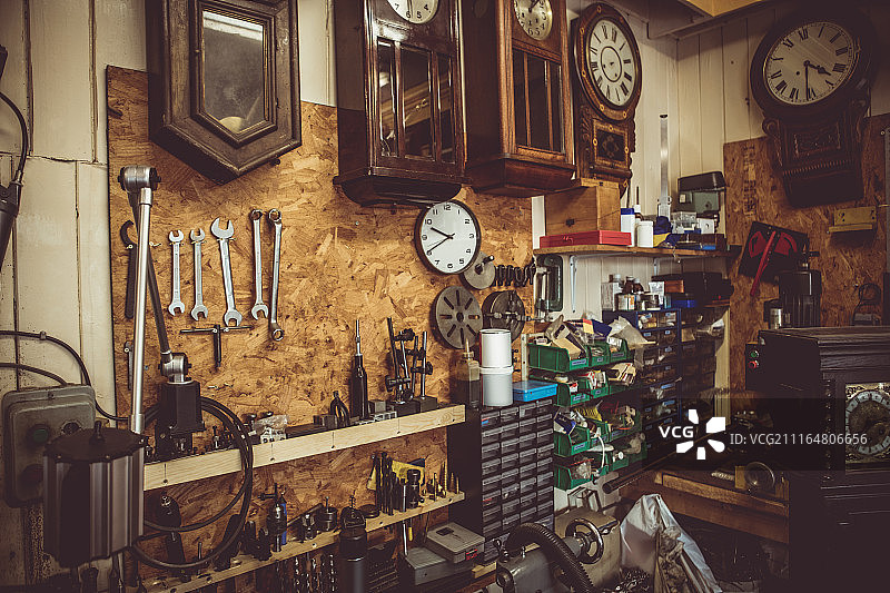 钟表师车间，墙上有钟表修理工具、设备和钟表图片素材