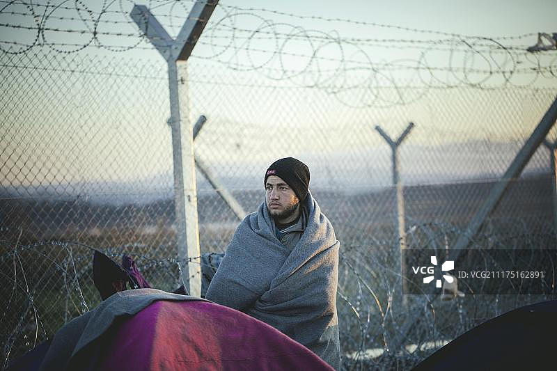 希腊-马其顿边境的伊多梅尼难民营，一名难民在欧洲希腊马其顿中部的伊多梅尼边境围栏前图片素材