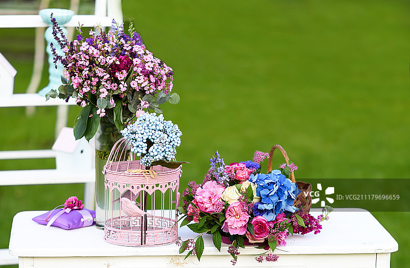复古的婚礼装饰，白色的桌子，鲜花和鹦鹉笼。图片素材
