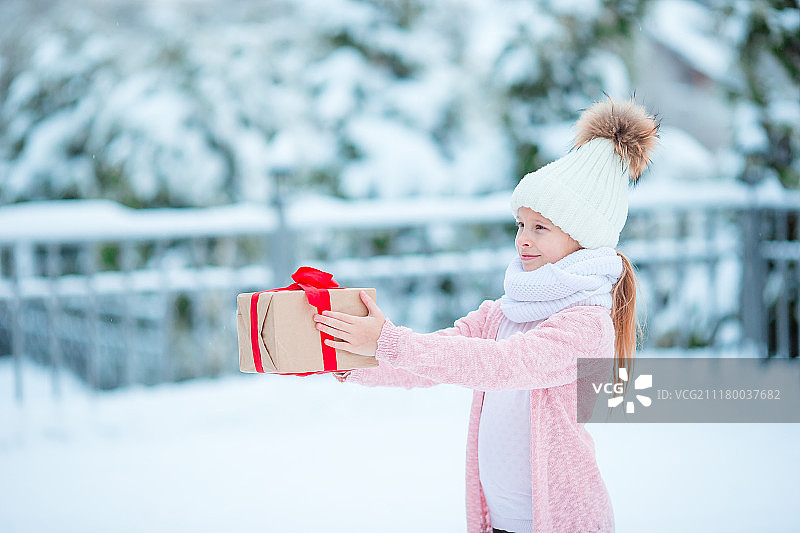 可爱的女孩与圣诞盒子礼物在冬天户外在圣诞夜图片素材