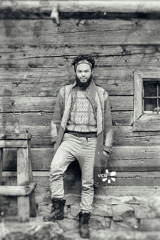 年轻潮人的肖像，男人的胡子在老旧的木屋前图片素材