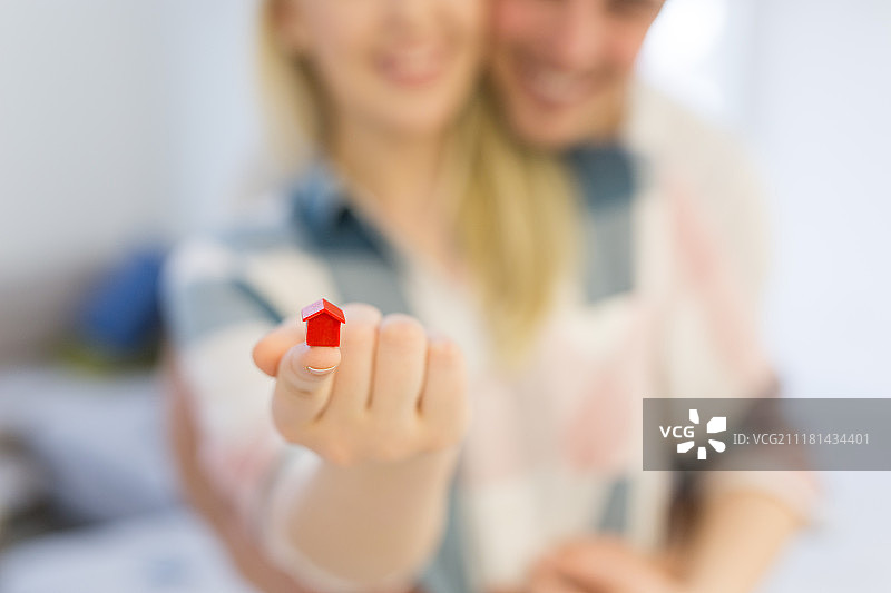 幸福的夫妇拥抱和展示小红房子在手中买房子开始一个家庭的概念图片素材