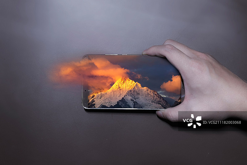 手机屏幕中的日照金山3D云雾效果图片素材