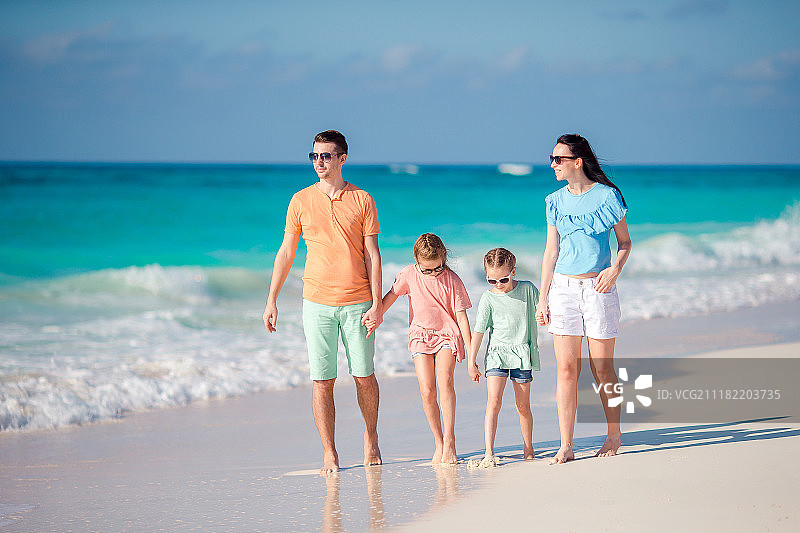 父母带着两个小女儿沿着沙滩散步图片素材