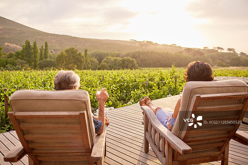 情侣放松，在阳光明媚，田园诗般的度假村露台上喝葡萄酒图片素材