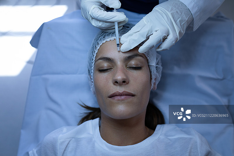 高角度视角的外科医生给整容手术注射在白种人的脸在诊所图片素材