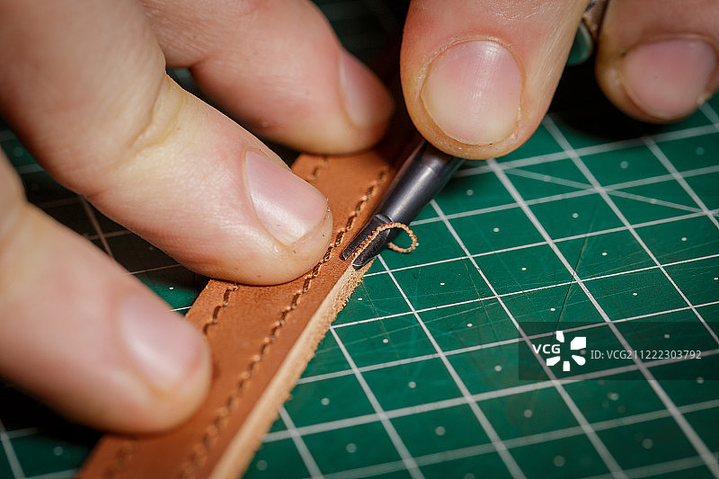 一个在皮革作坊工作的工匠正在削角图片素材