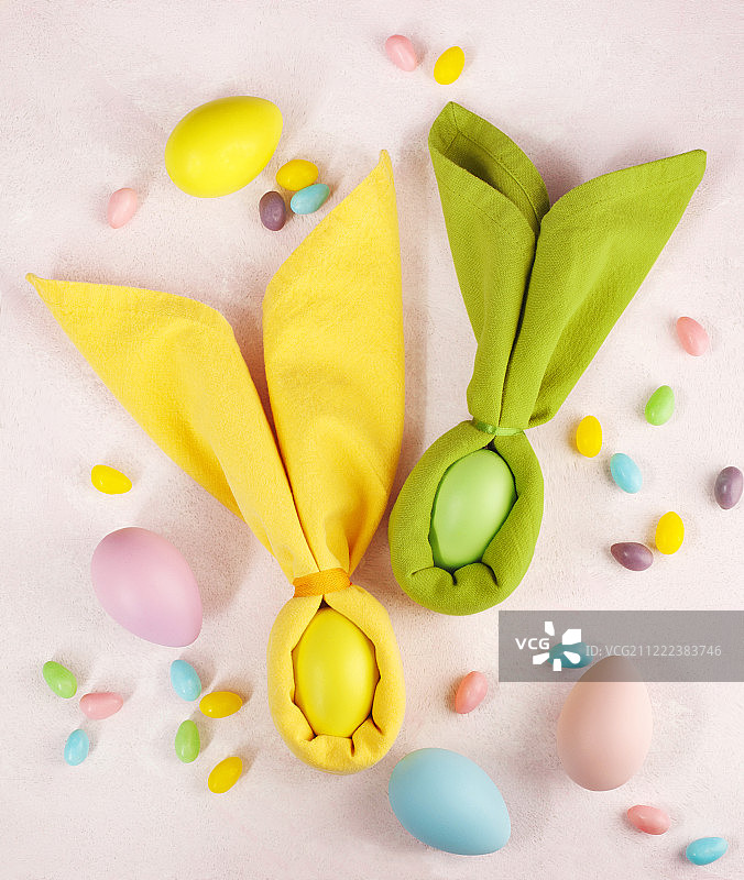 餐巾复活节兔子，装饰蛋和复活节糖果在粉红色的Ba图片素材