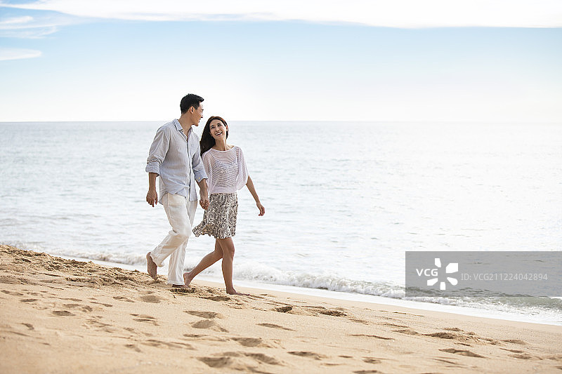 快乐的年轻夫妇在沙滩散步图片素材