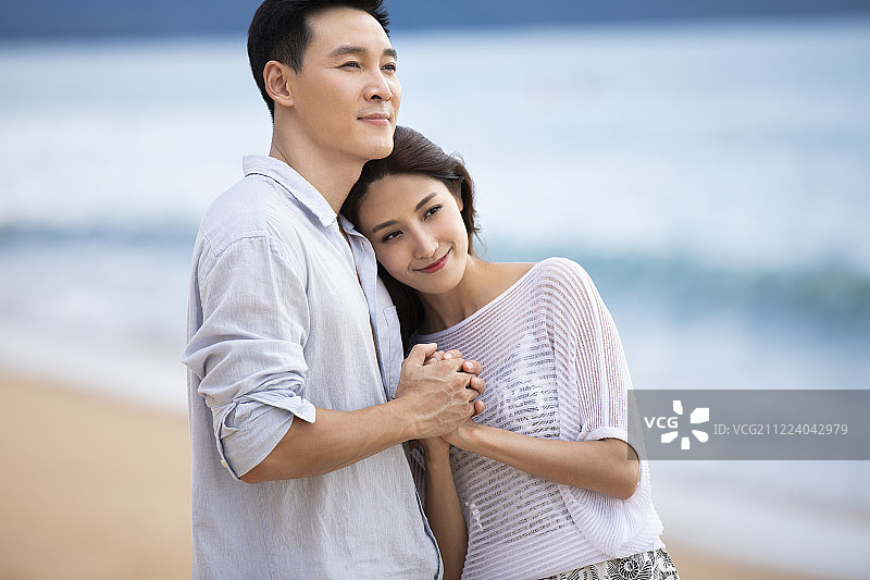 快乐的年轻夫妇在沙滩拥抱图片素材