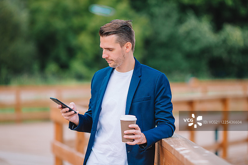 快乐的年轻城市男人工作和喝咖啡在欧洲城市户外图片素材