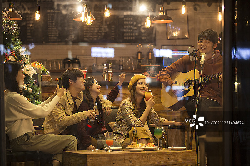 五个青年男女在酒吧弹吉他唱歌喝酒一起欢度圣诞节平安夜图片素材