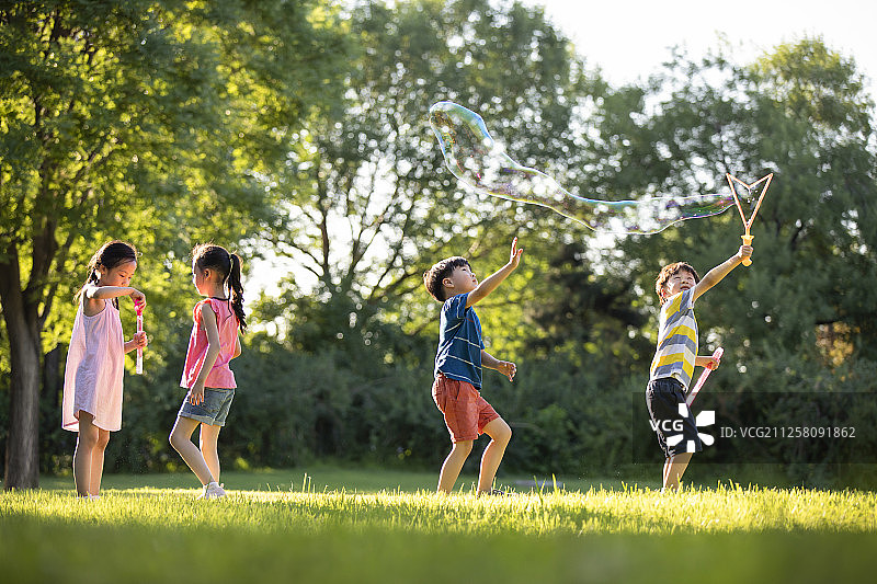快乐的儿童在草地上吹泡泡图片素材