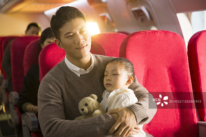爸爸抱着女儿在飞机上睡觉图片素材