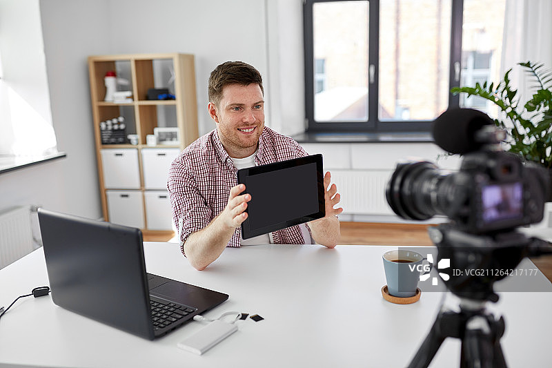 博客，视频博客和人的概念-男性博客用相机记录视频评论平板电脑在家里的办公室。男性博主在家里用平板电脑写视频博客图片素材