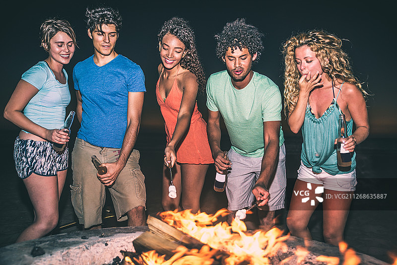 一群朋友点燃篝火，在海滩上玩图片素材