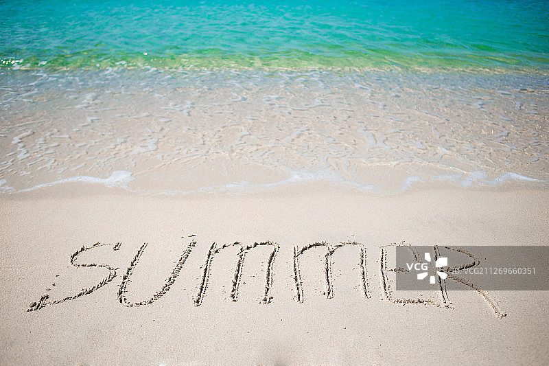 Word Summer手写在沙滩上，背景是柔和的海浪图片素材