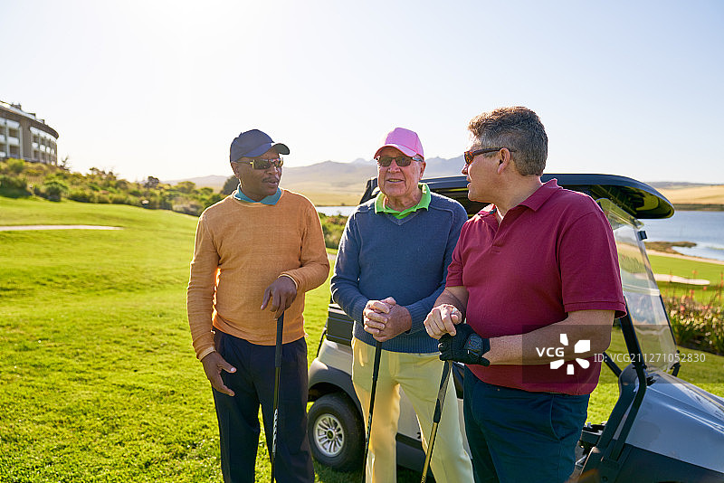 成熟的男性高尔夫球手在阳光明媚的高尔夫球车上聊天图片素材