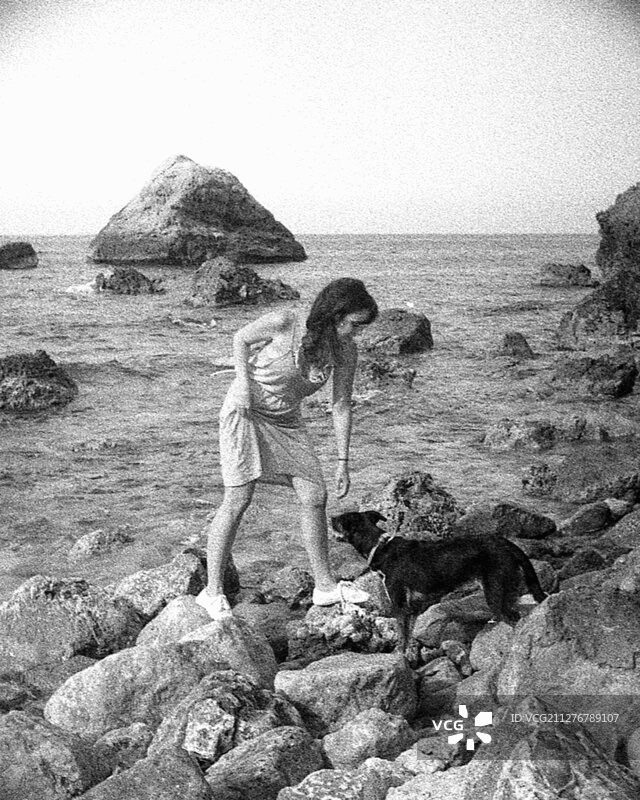 女人与狗在岩石海岸，3D立体效果图片素材