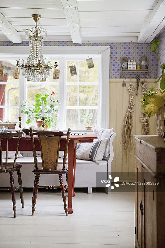 斯堪的纳维亚乡村别墅厨房里红色餐桌旁的旧椅子图片素材