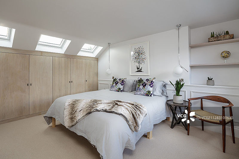 白色的卧室，米色的衣柜下面倾斜的天花板和天窗图片素材
