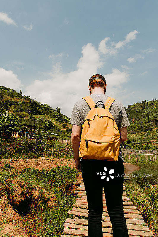 一个背着橙色背包的游客走在卢旺达的木板路上图片素材