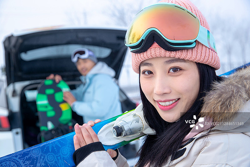 汽车后的年轻情侣扛着滑雪板图片素材