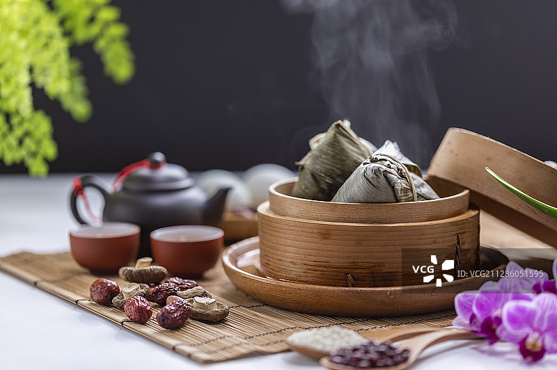 一笼美味的粽子旁边放着香菇红枣和茶壶茶杯图片素材