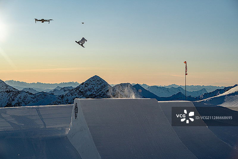 在为2022年世界杯和冬季奥运会进行的清晨训练中，滑雪运动员和两架无人机在高空飞行图片素材