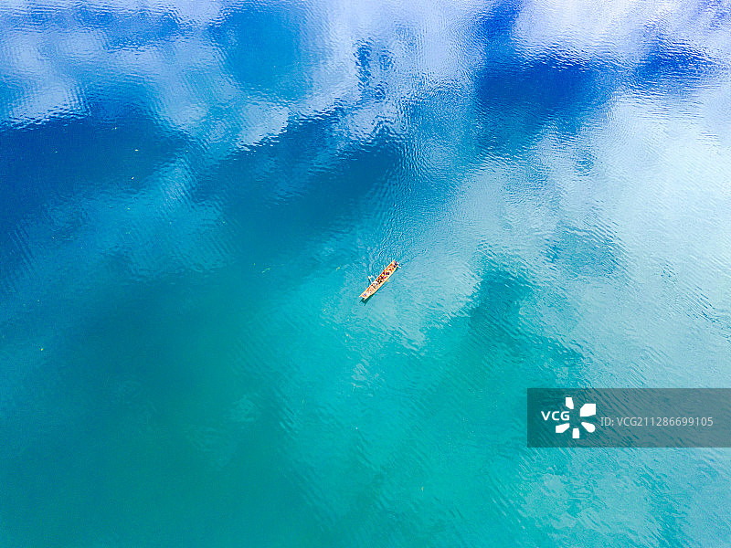 航拍蓝天白云反射下的泸沽湖面划船的人图片素材