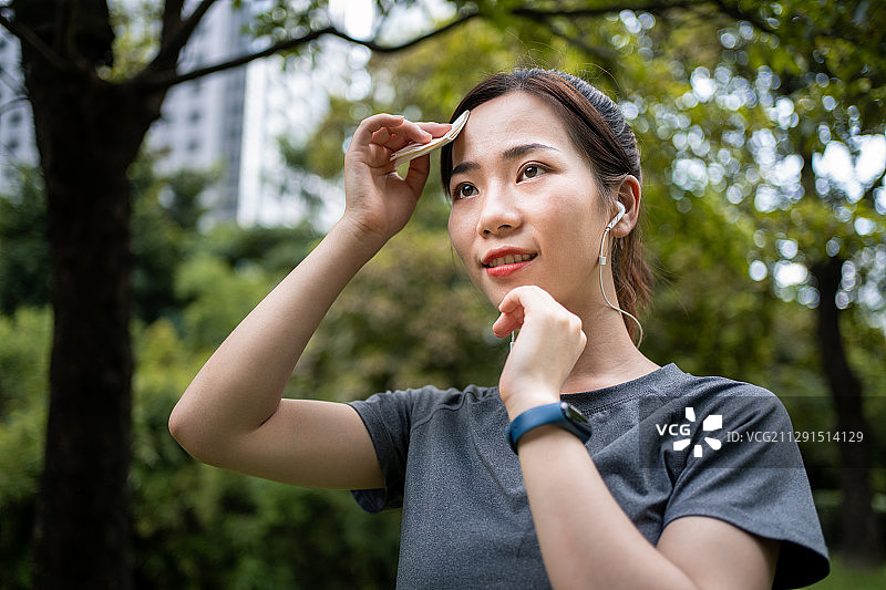 亚洲年轻女性运动后用纸巾擦汗图片素材