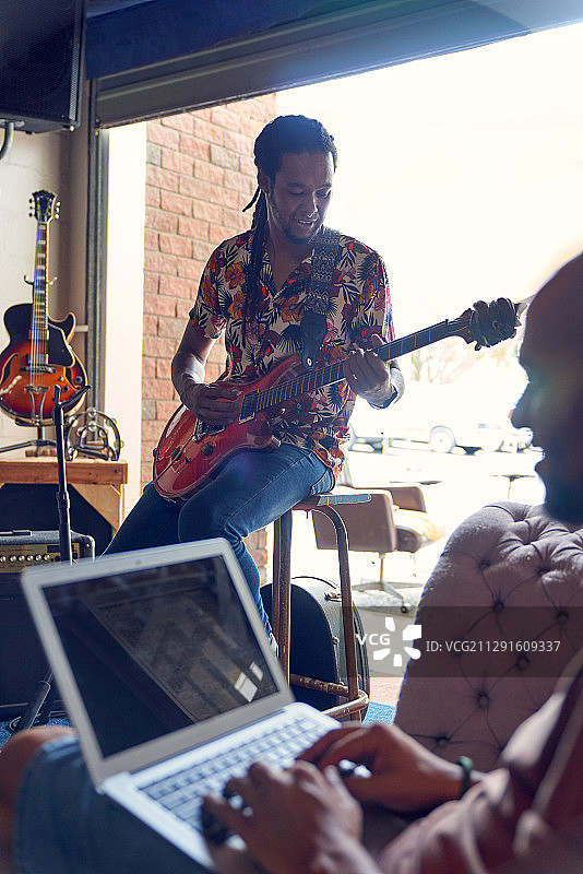 男音乐家用笔记本电脑和吉他在录音室练习图片素材