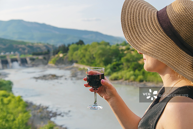 戴草帽的女人拿着一杯红酒，佐治亚州图片素材