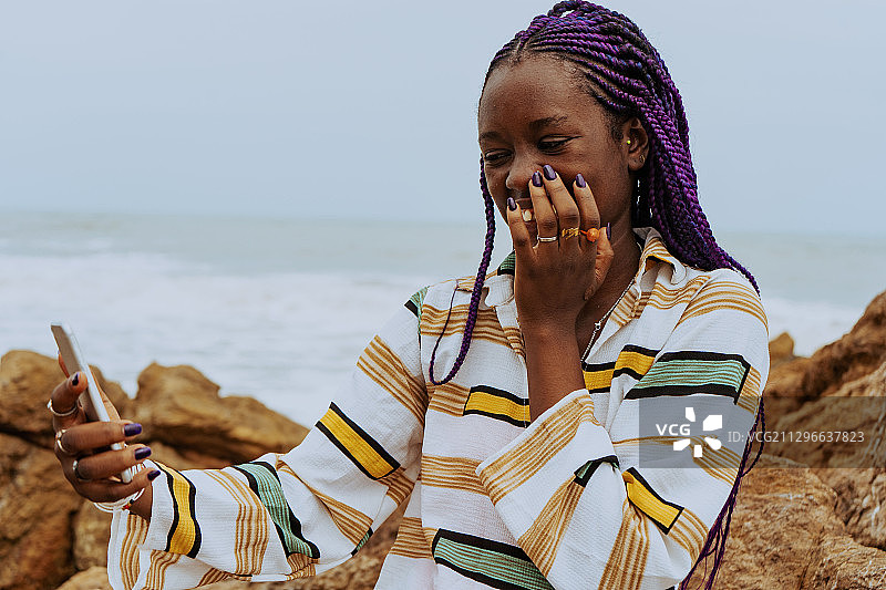 加纳，卡索阿，一名黑人妇女站在沙滩上使用手机图片素材
