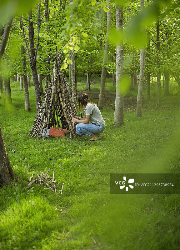 在树林里做树枝帐篷的女人图片素材