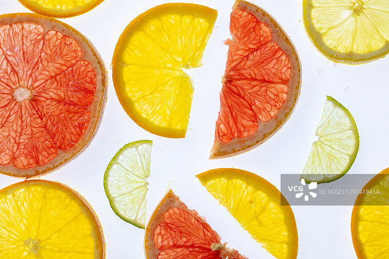 在白色的背景上用各种背光的柑橘片组成的抽象构图图片素材